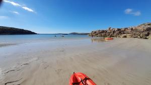 a red kayak sitting on a beach next to the water at Biddys cottage in Donegal