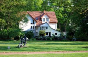 a white house with a red roof in the grass at Haus Geistmeier in Lippstadt