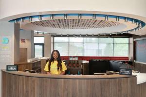 a woman standing behind a counter in a waiting room at Tru By Hilton Frisco Dallas, Tx in Frisco