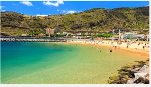 a beach with a bunch of people in the water at Casa da Avó in Machico