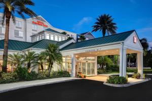 a hotel front of a building with palm trees at Hilton Garden Inn Fort Myers in Fort Myers