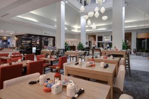 a restaurant with wooden tables and chairs and a cafeteria at Hilton Garden Inn Fort Myers in Fort Myers