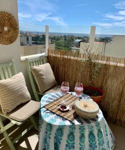 uma mesa com dois copos de vinho numa varanda em Sun & Sea rooftop em Costa da Caparica