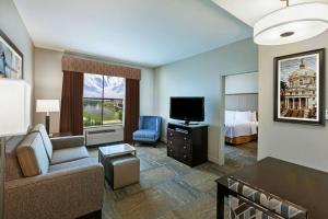 ein Hotelzimmer mit einem Bett, einem Sofa und einem TV in der Unterkunft Homewood Suites by Hilton Waco in Waco