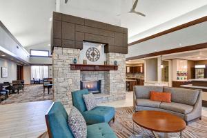 ein Wohnzimmer mit einem Kamin mit Sofas und einem Tisch in der Unterkunft Homewood Suites by Hilton Kansas City/Overland Park in Overland Park