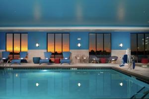 ein Pool in einem Hotel mit blauen Stühlen und Tischen in der Unterkunft Hampton Inn Burley in Burley