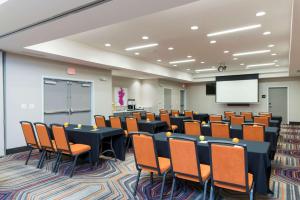 una sala de conferencias con mesas, sillas y una pantalla en Hampton Inn & Suites West Lafayette, In, en West Lafayette
