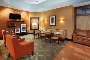 a waiting room with chairs and tables and a couch at Hampton Inn Birch Run in Birch Run