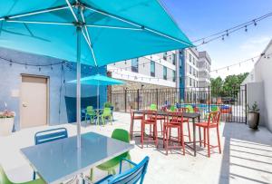 un patio con mesas, sillas y una sombrilla azul en Home2 Suites By Hilton Daphne Spanish Fort en Daphne