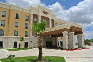 a hotel with a palm tree in front of it at Hampton Inn Carrizo Springs in Carrizo Springs