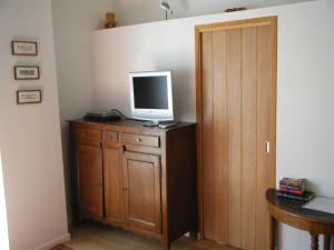 a television on top of a wooden cabinet with a door at La Source in Condette
