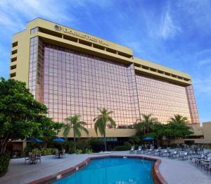a hotel with a swimming pool in front of a building at DoubleTree by Hilton Hotel Miami Airport & Convention Center in Miami