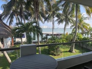 a balcony with a chair and palm trees and the ocean at Sina Suites Cancun in Canc&uacute;n