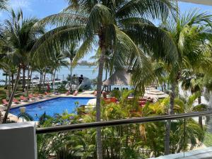 a view of a resort with a swimming pool and palm trees at Sina Suites Cancun in Canc&uacute;n