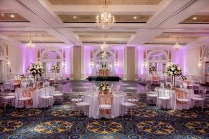 un salón de baile con mesas y sillas blancas e iluminación púrpura en Hotel Roanoke & Conference Center, Curio Collection by Hilton en Roanoke