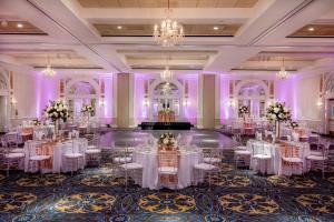 un salón de baile con mesas y sillas blancas e iluminación púrpura en Hotel Roanoke & Conference Center, Curio Collection by Hilton, en Roanoke