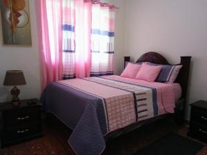 a bedroom with a bed with a pink blanket and a window at Hostal María Fernanda in Santo Domingo