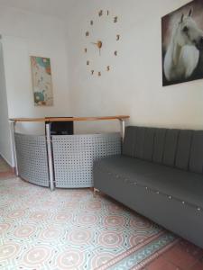 Hostal María Fernanda في سانتو دومينغو: غرفة معيشة مع أريكة وساعة على الحائط
