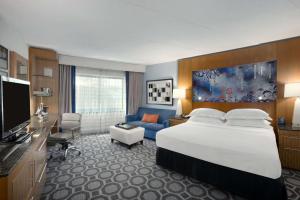 メルビルにあるヒルトン ロング アイランド / ハンティントンの大きなベッドとソファが備わるホテルルームです。