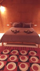 a bedroom with a bed with a red and white carpet at Pondok Indah Bungalows Tetebatu in Tetebatu