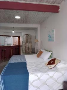 a bedroom with a large white bed and a kitchen at Loft Térreo no Centro in Búzios