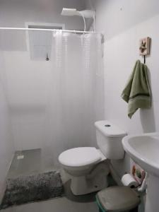 a white bathroom with a toilet and a sink at Loft Térreo no Centro in Búzios