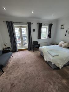 a bedroom with a bed and a couch and windows at Camden, London, Holloway Rooms 20 Busby Place, NW5 2SR in London