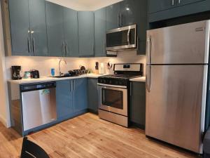 a kitchen with blue cabinets and stainless steel appliances at Deluxe Studio minutes from NYC! in Union City