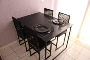 una mesa negra con sillas y un plato. en Casa 02 Quartos Condomínio Aceita Pet en Ourinhos