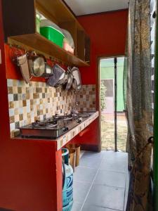 cocina con fogones y pared roja en Charity Pension House en San Vicente