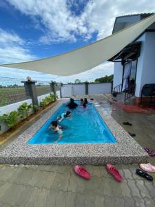 a group of people laying in a swimming pool at Murni Inn Kampung Perigi in Yan