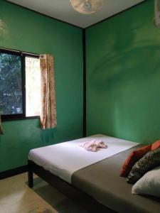 a bedroom with a green wall with a bed and a window at Charity Pension House in San Vicente