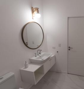 La salle de bains blanche est pourvue d'un lavabo et d'un miroir. dans l'établissement Montaña Domesticada, à San Martín de los Andes