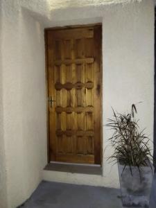 une porte en bois dans un bâtiment blanc avec une plante en pot dans l'établissement Monoambiente, à Mercedes