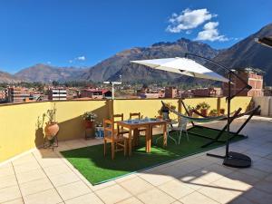 a table and chairs and an umbrella on a roof at Chaska valle Inn in Urubamba