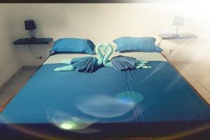 a large bed with blue sheets and blue pillows at L'Escale du Plaisir in Grande Savane