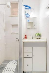 a white bathroom with a sink and a shower at Apto perto de Itaipava in Petrópolis