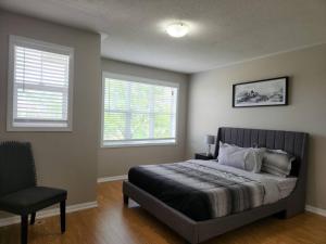 a bedroom with a bed and a chair and two windows at Beautiful home away from home in Milton