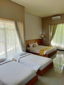 sypialnia z 2 łóżkami i oknem w obiekcie Surya Palace Syariah w mieście Padang