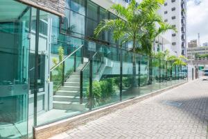 una fachada de cristal de un edificio con escaleras y palmeras en Beach Class Santa Maria by Easy Home en Recife