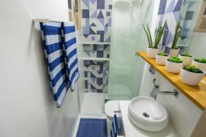 a bathroom with a toilet and a sink and plants at Areia Preta Park Studio | Salma Haddad in Guarapari