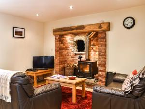 a living room with couches and a brick fireplace at Llandremor Fawr Cottage in Llanedy