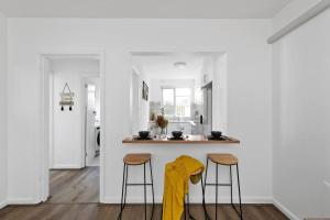 a kitchen with two stools and a counter with a yellow towel at Serene Coastal Haven in Melbourne +10 photos