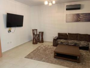 Il comprend un salon doté d'un canapé et d'une télévision à écran plat. dans l'établissement F5 -5 bedrooms Apt- Residence Hasnaoui avec parking Oran Algeria, à Oran