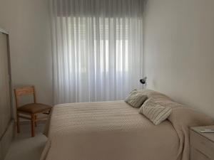 a bedroom with a bed and a chair and a window at Departamento céntrico y espacioso en Río Cuarto II in Río Cuarto