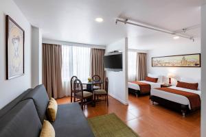 a hotel room with a couch and a bed and a table at Hotel Vilar América in Bogotá