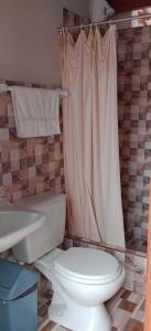 a bathroom with a toilet and a shower curtain at Travelershouse Casa Hospedaje in Huanchaco