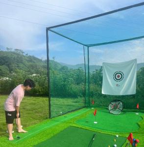 a woman playing a game of golf in a batting cage at Caofong Glamping Village Hoà Bình in Hòa Bình
