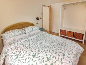 a bedroom with a bed with a green and white comforter at Wrens Nest in Chippenham