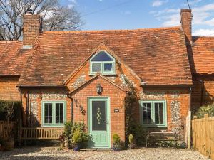 a red brick house with a green door at Burwood Cottage in Rotherfield Peppard